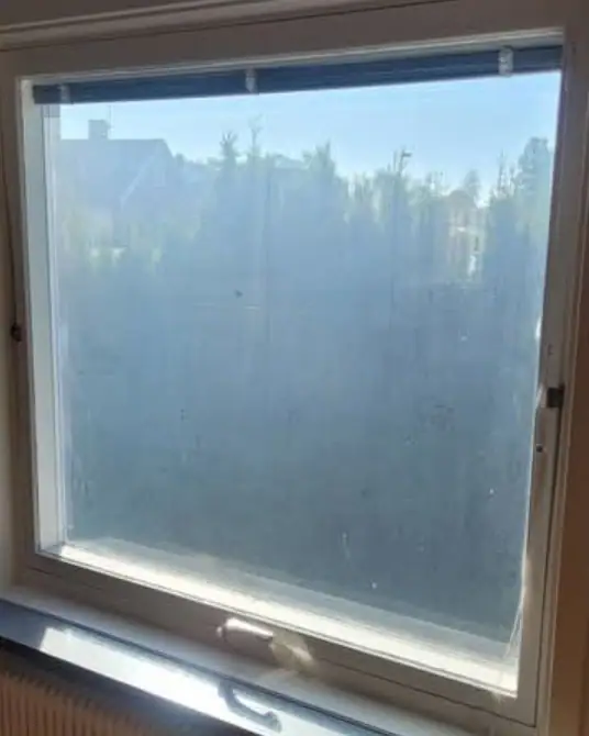 Fönster med smutsig, grå ruta före fönsterputs